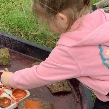 Acorns Nursery Child painting outdoors